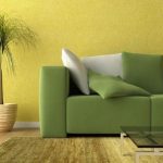 Зеленый диван на фоне желтой стены