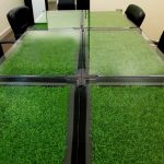 Практичный вариант с искусственной травой, спрятанной под стеклом стола