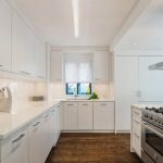Белая просторная кухня с высокими шкафчиками и пеналами