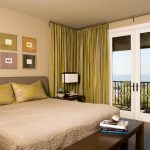 Бледные желто-зеленые шторы используются в спальне с песочными обоями