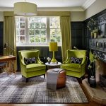 Зеленые кресла ,абажур и шторы разбавляют гостиную в черном цвете