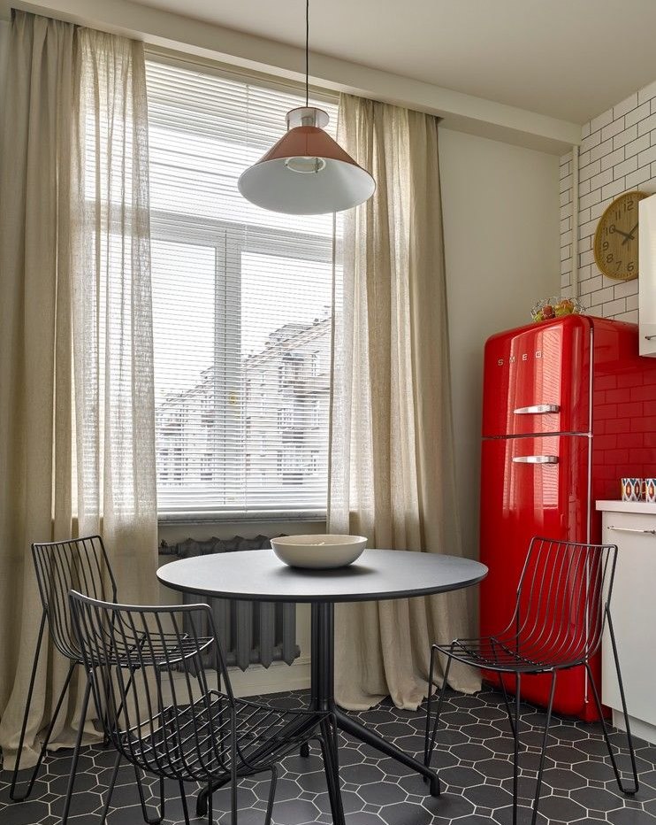 Красный холодильник около окна кухни с легкими шторами