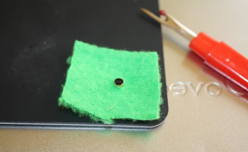 Пример установки люверса на куске зеленой ткани