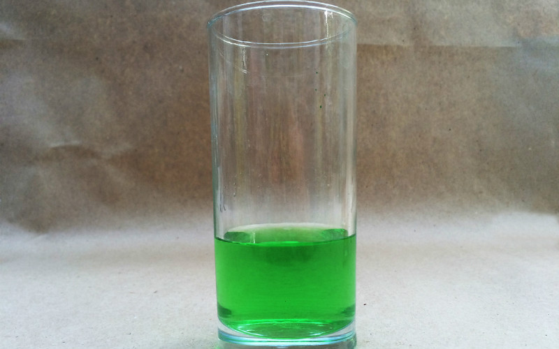 Стеклянный стакан с раствором зеленки для стирки