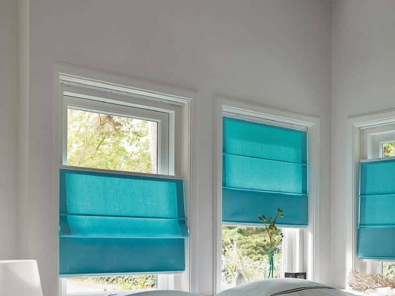 Голубые римские шторы на створках пластикового окна